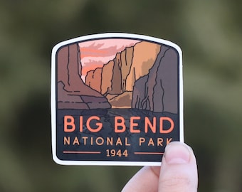 Puede incluir: Una pegatina del Parque Nacional Big Bend con un paisaje de cañones y una puesta de sol. La pegatina tiene un borde blanco y el texto "BIG BEND NATIONAL PARK 1944" en naranja y blanco.