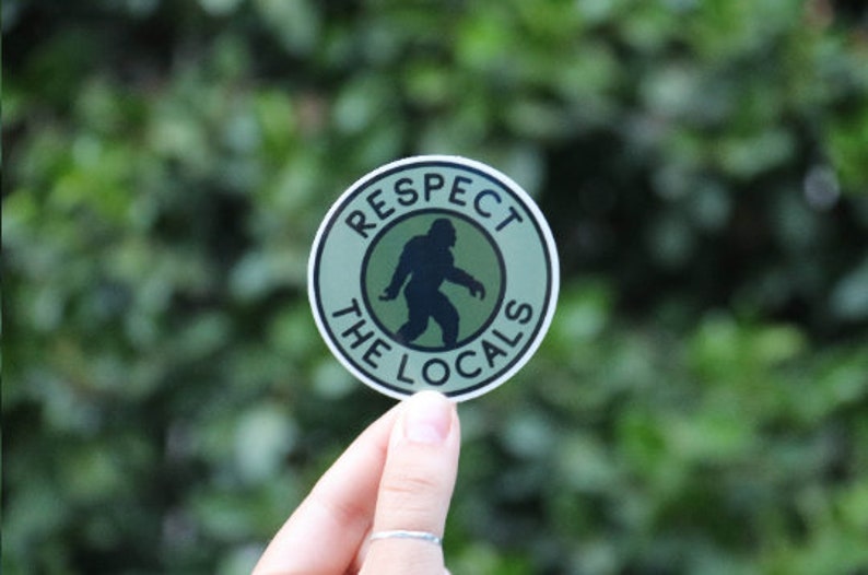 May include: A green and black round sticker with the text "Respect the Locals" and a silhouette of a Bigfoot inside a circle.