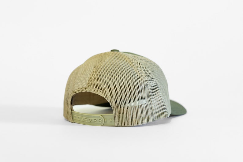May include: A green and beige mesh trucker hat with a plastic adjustable strap in the back.