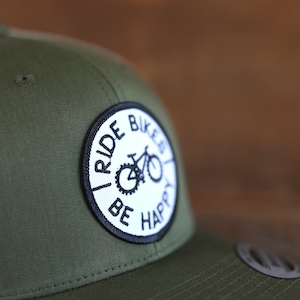 May include: A green and white trucker hat with a black and white patch that says "I Ride Bikes Be Happy" and a bicycle graphic.