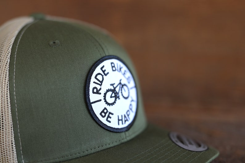 May include: A green and white trucker hat with a black and white patch that says "I Ride Bikes Be Happy" and a bicycle graphic.