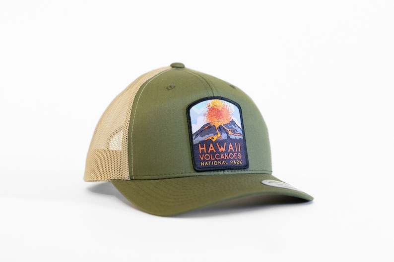 Op de afbeelding: Een groene en bruine truckercap met een patch met een uitbarstende vulkaan en de tekst "Hawaii Volcanoes National Park".