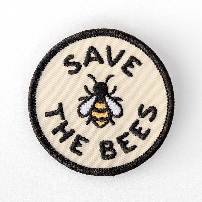 Centered on a plain white background, the Save The Bees patch shows its embroidered bee in gold, white and black.