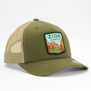 May include: A green and tan trucker hat with a patch that says "Zion National Park" and features a scenic view of the park.