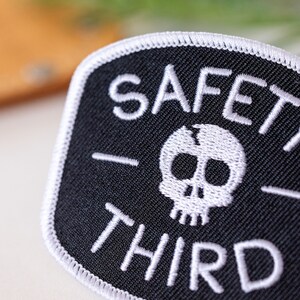 An angled close view crops the lettering of the Safety Third patch, showing raised white thread and edge stitch.