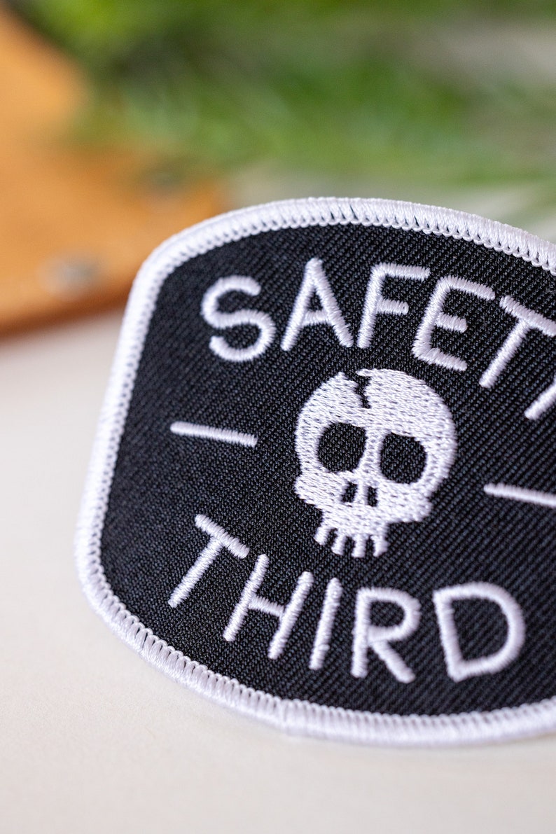 An angled close view crops the lettering of the Safety Third patch, showing raised white thread and edge stitch.