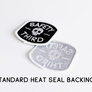 Two Safety Third patches, one flipped to show the grey heat seal backing, with text noting standard backing.