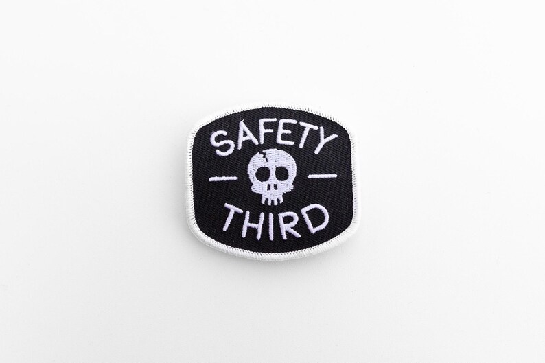 Centered on a plain white background, the small Safety Third patch shows its skull between two dashes.