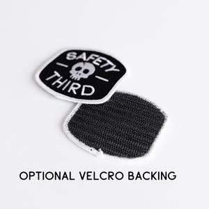 One Safety Third patch lies face up beside another turned over to reveal black loop velcro backing.