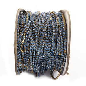 May include: A spool of blue rhinestone trim with gold metal settings. The trim is wound around a cardboard spool.