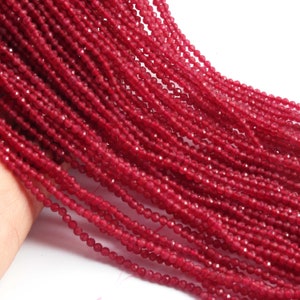 May include: A strand of deep red faceted gemstone beads. The beads are small and uniform in size, creating a smooth and elegant look.