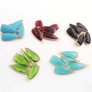 Peut inclure: Assortiment de pendentifs en pierres précieuses avec des anneaux de saut dorés. Les pendentifs sont de différentes couleurs, notamment turquoise, rouge, noir, vert et bleu.