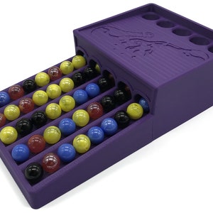 Könnte beinhalten: Lilafarbenes Murmelbahn-Spiel mit einer Bahn, die zu einer Reihe von Löchern oben führt. Die Bahn ist mit bunten Murmeln gefüllt.