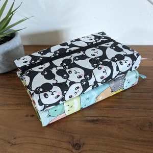 Puede incluir: Dos estuches de l&aacute;pices de tela apilados uno encima del otro. El estuche superior es blanco y negro con un patr&oacute;n de oso panda. El estuche inferior es multicolor con una variedad de patrones de animales.