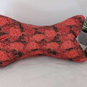 May include: A red and black patterned pillow with a bow tie shape. The pattern features swirling clouds.