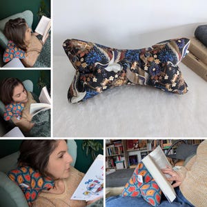 Puede incluir: Un cojín de lectura negro y azul con un diseño de grúa. El cojín tiene forma de pajarita y es perfecto para apoyar los libros mientras se lee.