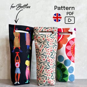 Könnte beinhalten: Drei Stoff-Weinflaschenbeutel. Einer ist schwarz mit bunten Figuren, ein anderer hat einen beigen Hintergrund mit roten Beeren und grünen Blättern, und der dritte hat einen weißen Hintergrund mit einem floralen Design. Die Beutel haben oben einen Griff.