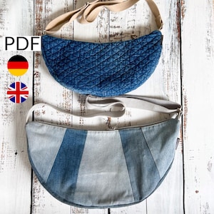 Könnte beinhalten: Zwei halbmondförmige Taschen aus Denim mit verstellbaren Trägern. Die obere Tasche ist gesteppt und die untere Tasche hat ein Patchwork-Design.