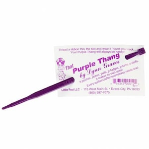May include: Purple plastic tool called "That Purple Thang by Lynn Graves". It is used for quilting and crafting. The tool is purple and has a slot for a ribbon. The packaging includes the text "Thread a ribbon thru the slot and wear it 'round your neck. Your Purple Thang will always be handy!" and contact information for Little Foot LLC.