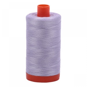 May include: A spool of lavender-colored thread with an orange plastic bobbin.