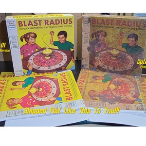 May include: Two vintage board game boxes for the game "Blast Radius". The boxes are yellow with red and black accents. The game features a spinning target with numbers and a red and yellow ball. The boxes are labeled "Blast Radius" and "Use quick reaction and skill to get to a safe distance".