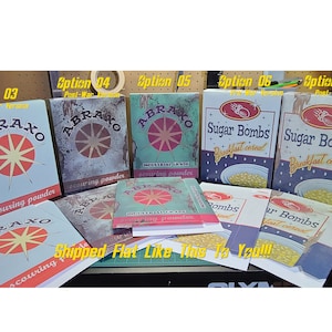 May include: A collection of vintage-style boxes featuring different designs. The boxes are labeled with the words "Abraxo scouring powder", "Sugar Bombs breakfast cereal", and "Abraxo industrial grade scouring powder". The boxes are in various shades of blue, red, and yellow, with a distressed, aged look.