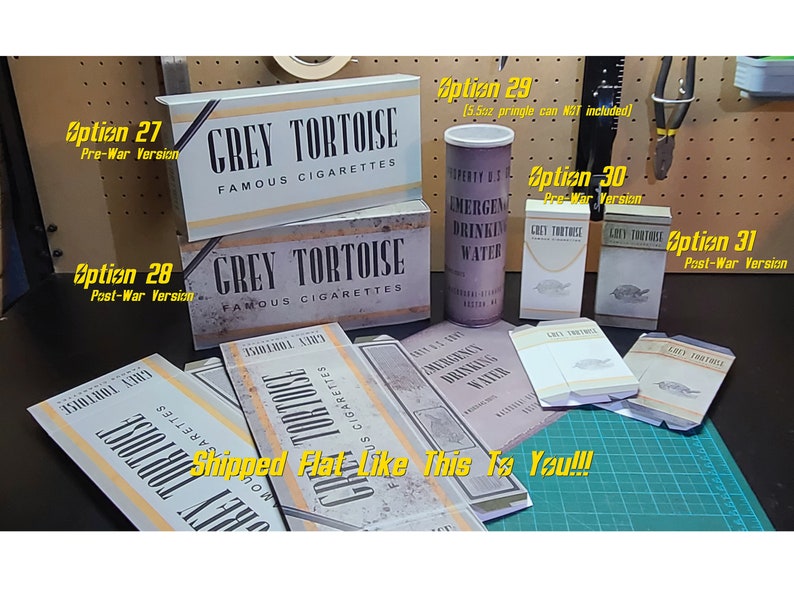 May include: Four different versions of a Grey Tortoise cigarette pack, two pre-war and two post-war, are shown laid flat.  The packs are all white with black lettering and a grey tortoise illustration.  A vintage can of Emergency Drinking Water is also shown.  The text "Shipped Flat Like This Is You!!" is written in yellow on a green surface.