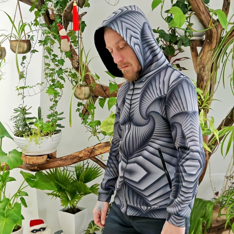 May include: A black and white zip-up hoodie with a geometric pattern. The hoodie has a hood with a drawstring and a zipper closure.