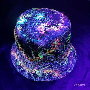 May include: A UV-active bucket hat with a psychedelic design. The hat has a complex pattern of neon green, blue, and orange lines and shapes against a dark background. The text "UV-Active" is visible on the bottom right.