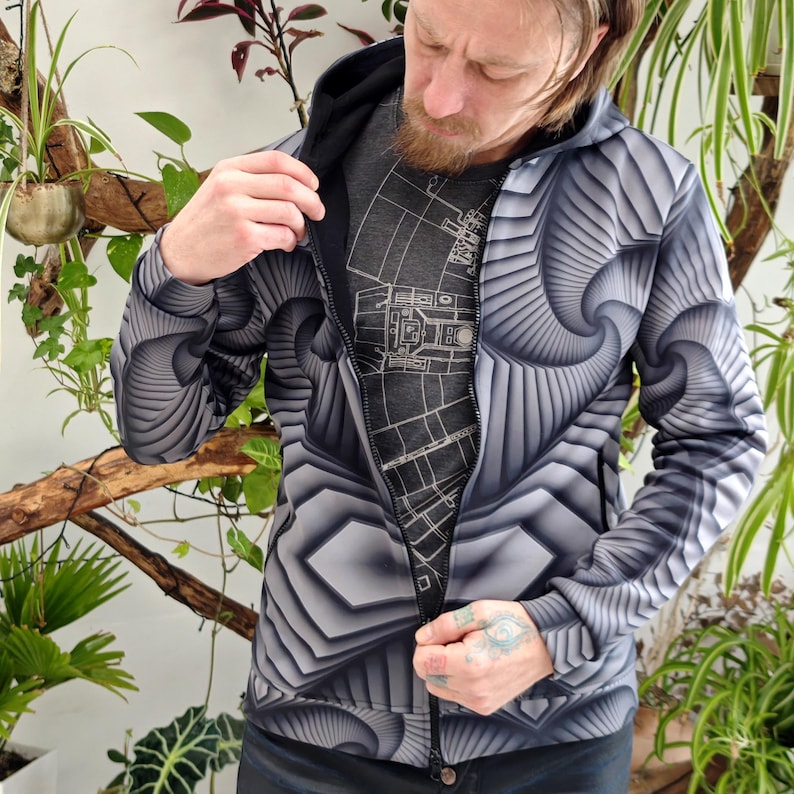 May include: A black and white hooded jacket with a geometric pattern. The zipper is partially open, revealing a gray t-shirt underneath.