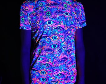 May include: A short-sleeved t-shirt with a vibrant, all-over pattern of stylized eyes in shades of blue, pink, orange, and green. The shirt glows under UV light, with the text "UV-Active" visible at the bottom.