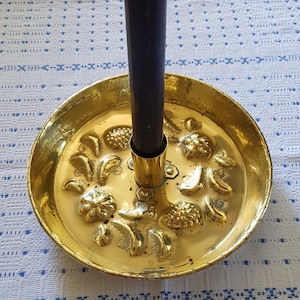 Peut inclure: Un bougeoir en laiton avec un motif décoratif de fruits et de feuilles. Le bougeoir contient une bougie noire.