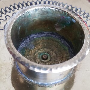 以下が含まれることがあります： 装飾的な波状の縁を持つ真鍮製のキャンドルホルダー。ホルダーは、キャンドル用の中央の穴のある円形のトップを持っています。