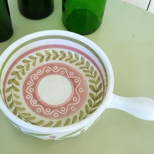 Puede incluir: Un plato de servir de cerámica blanca con asa. El plato tiene un diseño floral rosa y verde.