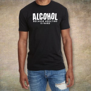 May include: A black t-shirt with white text that reads "ALCOHOL BECAUSE ADULTING IS HARD".