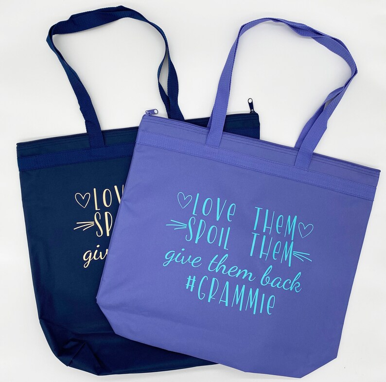 May include: Two tote bags, one blue and one purple, with the text "Love Them Spoil Them Give Them Back #Grammy" printed on the purple bag.