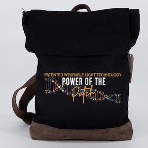 May include: Black canvas backpack with brown leather trim. The backpack has a flap with a graphic of a DNA strand and the text "PATENTED WEARABLE LIGHT TECHNOLOGY POWER OF THE Patch".