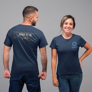 May include: Two navy blue t-shirts. The back of one shirt features a graphic of a DNA strand with the text "PATENTED WEARABLE LIGHT TECHNOLOGY POWER OF THE Patch". The front of the other shirt features a blue circle with the text "LIFEWAVE".