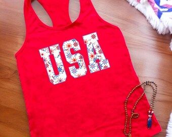May include: Red tank top with a white "USA" graphic featuring a blue and pink floral pattern.