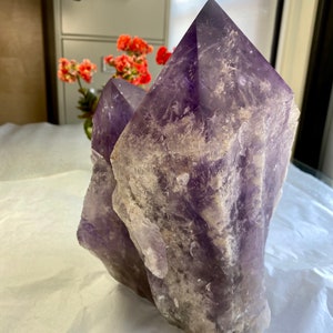 May include: A large, double-pointed amethyst crystal with a rough, natural texture. The crystal is a deep purple color with white inclusions.