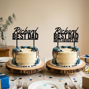 May include: Two round cakes with white frosting and dark chocolate ganache drips, topped with blue and grey swirls. Each cake features a black acrylic topper. One reads Richard BEST DAD, the other reads Richard BEST DAD HAPPY FATHER'S DAY.