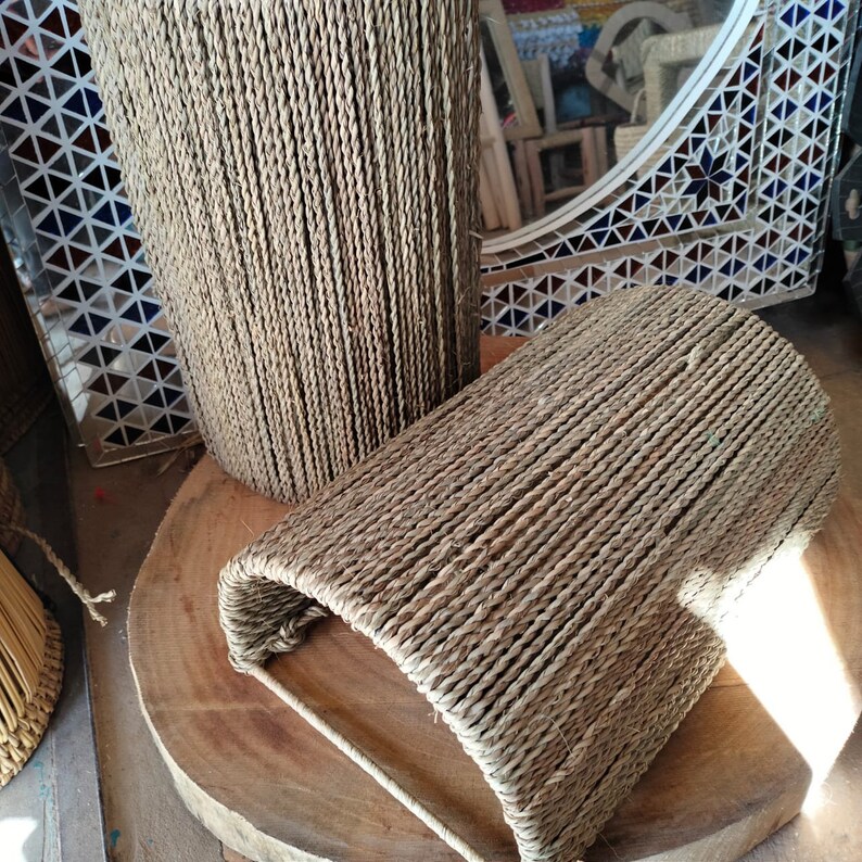 May include: Two woven baskets made of natural rope, one is cylindrical and the other is a half-cylinder shape. The baskets are sitting on a wooden surface.