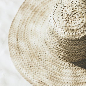 May include: A large, wide-brimmed straw hat with a woven texture. The hat is light beige in color and has a slightly rounded crown.