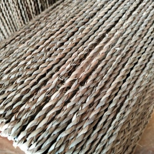 May include: Close-up of a woven texture made of natural fibers. The fibers are woven in a diagonal pattern, creating a textured surface.