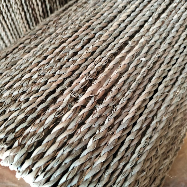 May include: Close-up of a woven texture made of natural fibers. The fibers are woven in a diagonal pattern, creating a textured surface.