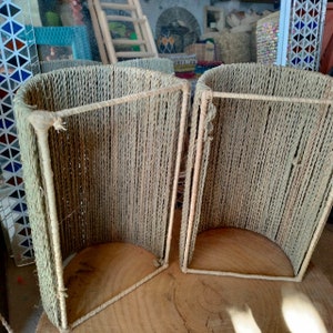 May include: Two woven lampshades made of natural rope, with a rectangular frame. The lampshades are light brown and have a slightly curved shape.