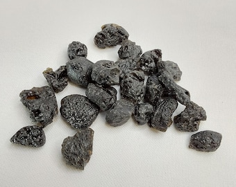 Könnte beinhalten: Eine Sammlung schwarzer Obsidian-Steine, auch bekannt als vulkanisches Glas, mit einer rauen, strukturierten Oberfläche. Die Steine sind in verschiedenen Größen und Formen.
