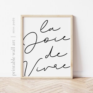 Puede incluir: Una impresi&oacute;n de arte de pared imprimible en blanco y negro con el texto "La Joie de Vivre" en una fuente cursiva.