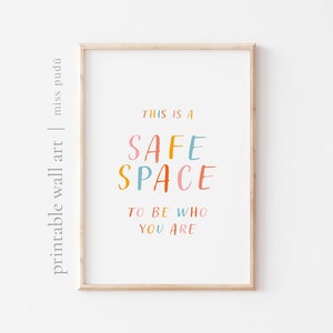 Può includere: Una stampa incorniciata con il testo "This is a safe space to be who you are." Il testo è in un font colorato e scritto a mano.