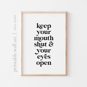 Può includere: Stampa incorniciata con la frase "keep your mouth shut & your eyes open" in grassetto e carattere nero. La stampa è su sfondo bianco e in una cornice di legno chiaro. Le parole "printable wall art" e il nome "miss pudú" sono stampate a sinistra.